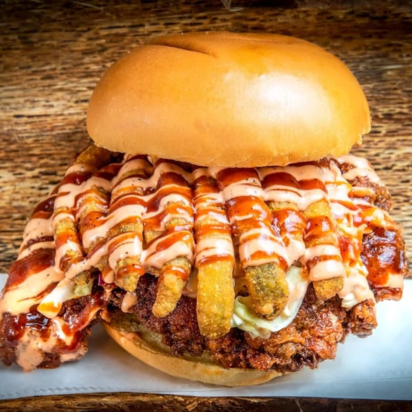 A Nashville hot chicken sandwich with fries, slaw, and two sauces on a bun.